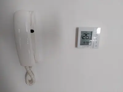 a white phone on a wall next to a clock at Brzeće Center Studio Mitrovski Gondola 300m in Kopaonik