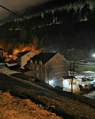 a building with cars parked in a parking lot at night at Vila Ivanović in Kopaonik