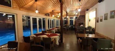 a dining room with tables and chairs and windows at Vila Ivanović in Kopaonik