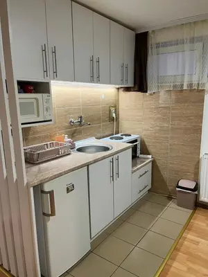 a kitchen with white cabinets and a sink and a microwave at Čarapan in Kruševac