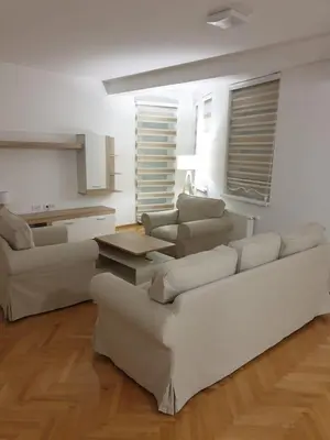 a living room with a white couch and a table at Dobi Apartmani WING in Jagodina
