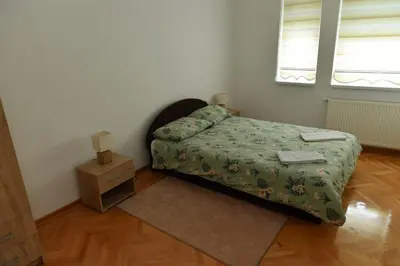 a small bedroom with a bed and a night stand at Dobi Apartmani WING in Jagodina