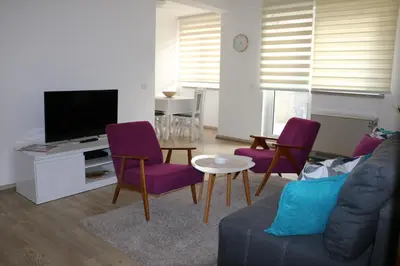 a living room with purple chairs and a tv at Apartmani MIBOR in Vrnjačka Banja