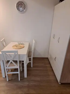 a white table and chairs in a room with a clock at Apartmani MIBOR in Vrnjačka Banja