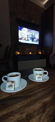 two cups of coffee on a wooden table with a television at Snow peak Wellness & Spa, Kopaonik Milmari N5 in Kopaonik
