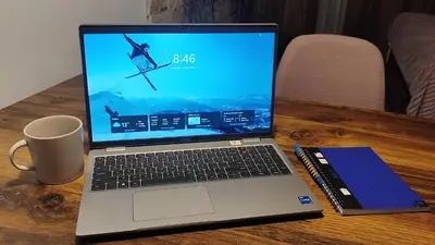 a laptop computer sitting on a wooden table with a book and a mug at Snow peak Wellness & Spa, Kopaonik Milmari N5 in Kopaonik