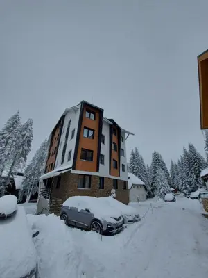 a building with a car parked in the snow at Apartman Djordje-vila Montana in Kopaonik