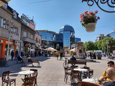 a group of people sitting at tables in a city street at suvi centar in Niš