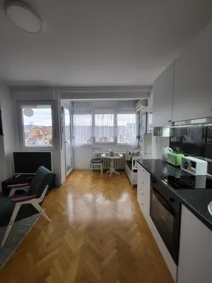 a kitchen with a counter top and a living room at Happy Place in Niš