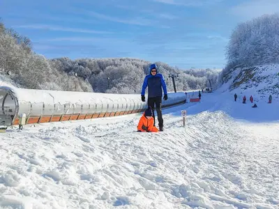 a woman standing next to a child in the snow at Guesthouse Junior in Kopaonik