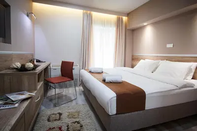 a hotel room with a large bed and a chair at Guesthouse Junior in Kopaonik