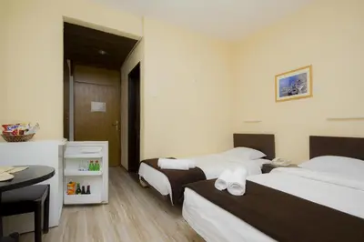 a hotel room with two beds and a desk at Guesthouse Junior in Kopaonik