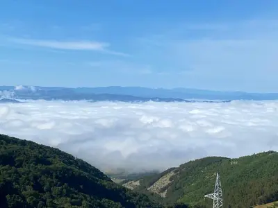an electricity pylon in the middle of a valley of clouds at Milmari Lux N8 in Kopaonik