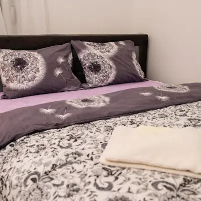 a bed with purple and white sheets and pillows at Godimento Vrnjačka Banja in Vrnjačka Banja