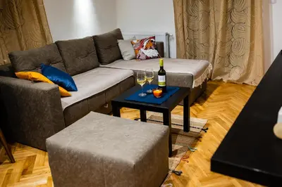 a living room with a couch and a table with wine glasses at Godimento Vrnjačka Banja in Vrnjačka Banja