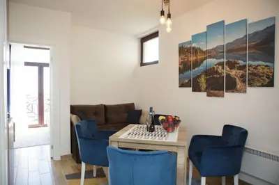 a living room with a table and blue chairs at Dvori Sky View E14 Kopaonik - free private parking in Kopaonik
