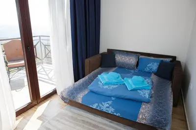 a bed with blue pillows in a room with a balcony at Dvori Sky View E14 Kopaonik - free private parking in Kopaonik