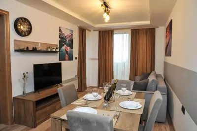 a living room with a table and a couch at Vila Planinsko Blago Luxury Apartmans in Kopaonik