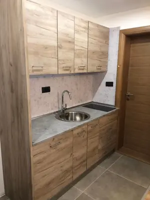a kitchen with wooden cabinets and a sink at Vila Planinsko Blago Luxury Apartmans in Kopaonik