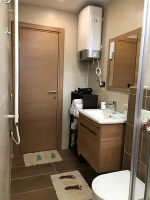 a bathroom with a sink and a toilet and a door at Vila Planinsko Blago Luxury Apartmans in Kopaonik