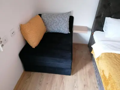a black couch with two pillows sitting next to a bed at MON Accommodation free parking in Niš