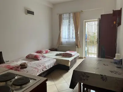 a room with two beds and a table and a kitchen at Mladenović smeštaj in Soko Banja