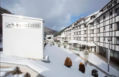 a building with snow on the ground in front of it at BRZECE SKI GONDOLA & FREE PARKING apartment in Kopaonik