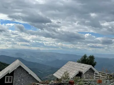 two houses on a hill with a view of mountains at Apartman Pahuljica in Kopaonik