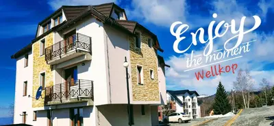 a building with a sign that reads enjoy the moment at WELLKOP Apartman Kopaonik in Kopaonik
