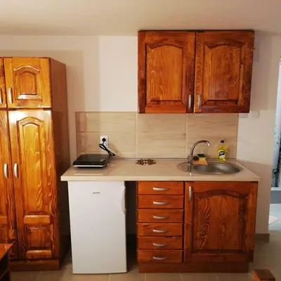 a kitchen with wooden cabinets and a sink at Sobe i apartmani Simic in Ribarska Banja
