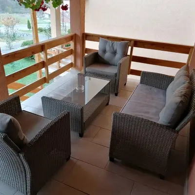 a patio with wicker chairs and a glass table at Sobe i apartmani Simic in Ribarska Banja