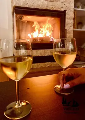 two glasses of white wine in front of a fireplace at Duplex Vidik B30 - 85m2 in Kopaonik