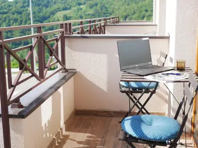 a laptop computer sitting on a desk on a balcony at DeltaLux apartmani Milmari Kopaonik in Kopaonik