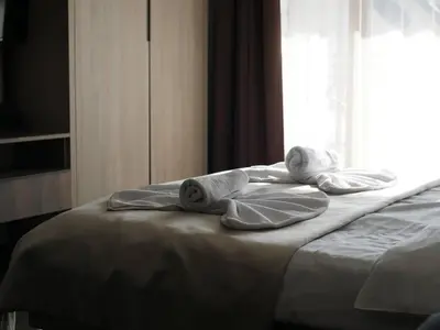 a bed with towels on it with a window at DeltaLux apartmani Milmari Kopaonik in Kopaonik