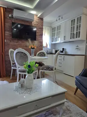 a kitchen and living room with a table and chairs at Apartman Hedonist in Vrnjačka Banja