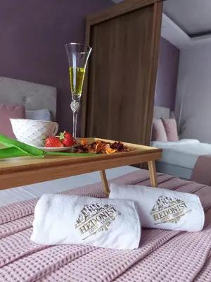 a table with a plate of food and a glass of wine at Apartman Hedonist in Vrnjačka Banja