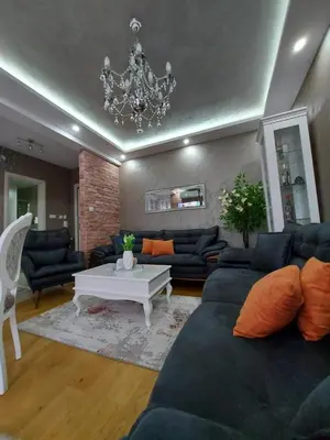 a living room with a blue couch and a chandelier at Apartman Hedonist in Vrnjačka Banja
