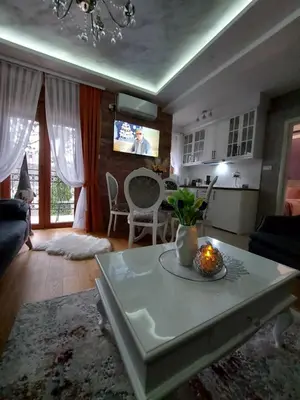a living room with a table and a kitchen at Apartman Hedonist in Vrnjačka Banja