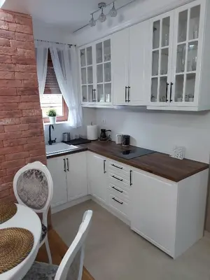 a kitchen with white cabinets and a brick wall at Apartman Hedonist in Vrnjačka Banja