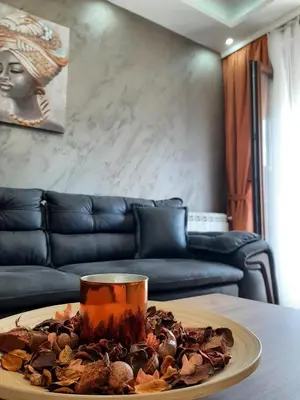 a table with a plate of food on a table with a couch at Apartman Hedonist in Vrnjačka Banja