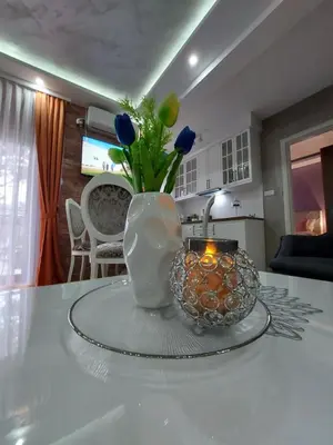 a vase with flowers and a candle on a table at Apartman Hedonist in Vrnjačka Banja