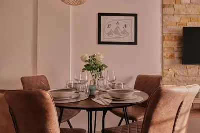 a dining room table with chairs and a table with flowers on it at L&N Apartmani Kopaonik-Milmari Resort in Kopaonik