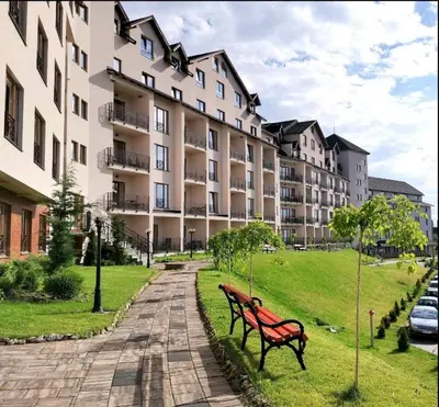 a red park bench in front of a large building at L&N Apartmani Kopaonik-Milmari Resort in Kopaonik