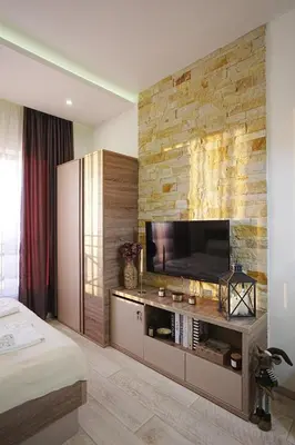 a bedroom with a flat screen tv on a stone wall at VitaDea Milmari Kopaonik in Kopaonik