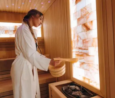 a woman standing in a sauna with a heater at VitaDea Milmari Kopaonik in Kopaonik