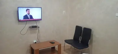 a room with a tv on a wall with a chair and a table at Mikassa room in Niš