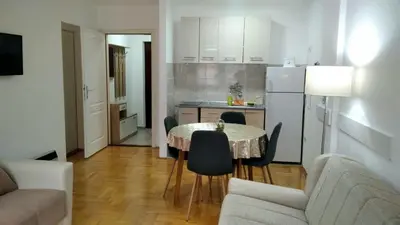 a living room with a table and chairs and a kitchen at Apartman Ristić 6 in Soko Banja