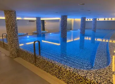 a large swimming pool with blue water in a building at Apartman DreamHome in Vrnjačka Banja