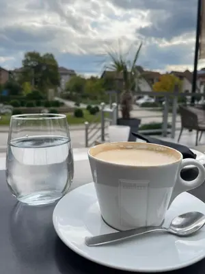a cup of coffee and a glass of water on a table at Apartman DreamHome in Vrnjačka Banja