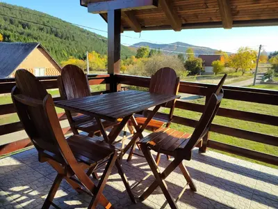 a wooden table and four chairs on a porch at Apartman Draškovic - Goč in Biserske Kuće